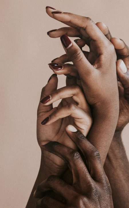 Home-Ueber-uns-1 Mehrere Hände unterschiedlicher Hauttöne übereinandergelegt in ruhiger, naher Komposition